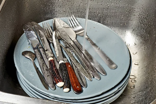 Dirty plates and cutlery in kitchen sink before washing — Stock Photo, Image