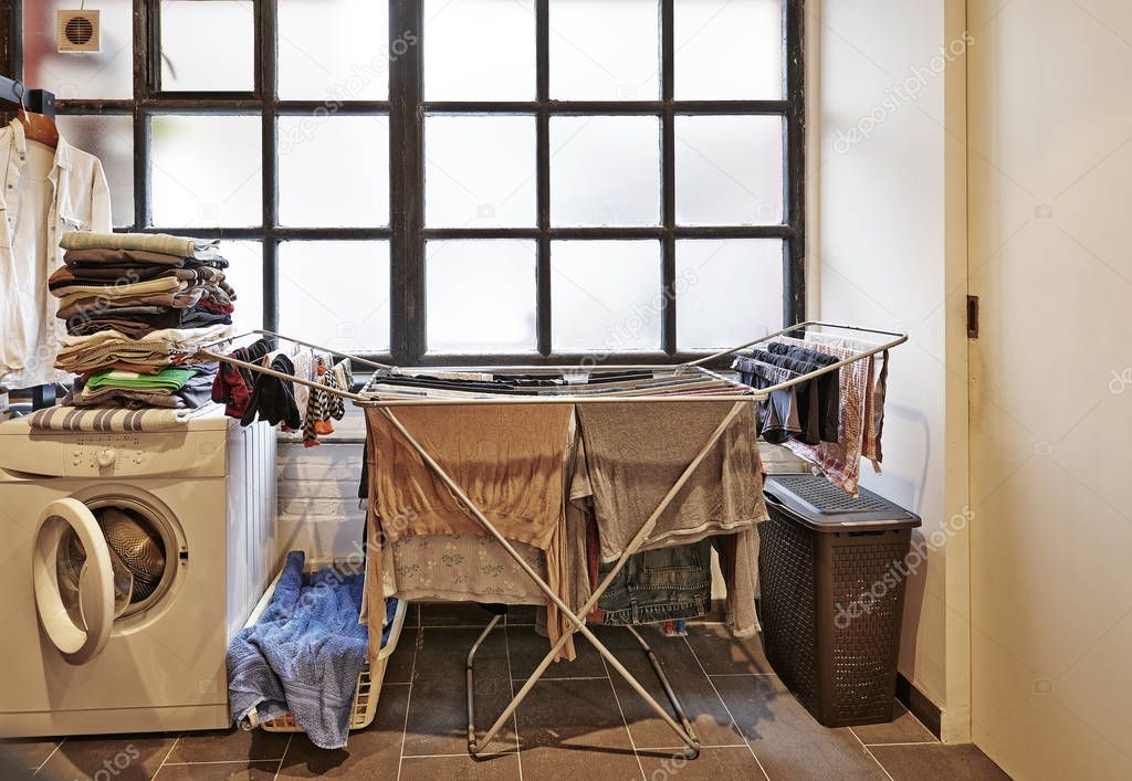 Untidy and messy male laundry room against windows