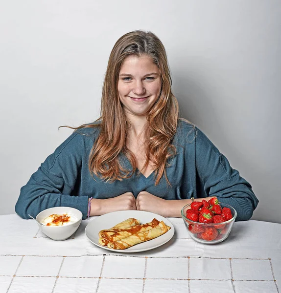 パンケーキとイチゴを食べる朝食のテーブルで女の子 — ストック写真