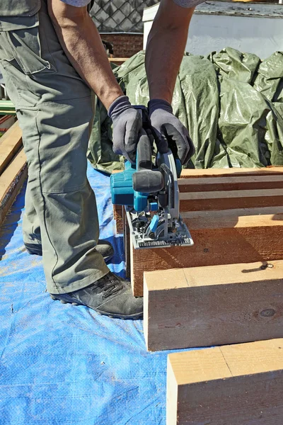 Kék galléros carpenter segítségével elektromos fűrész — Stock Fotó