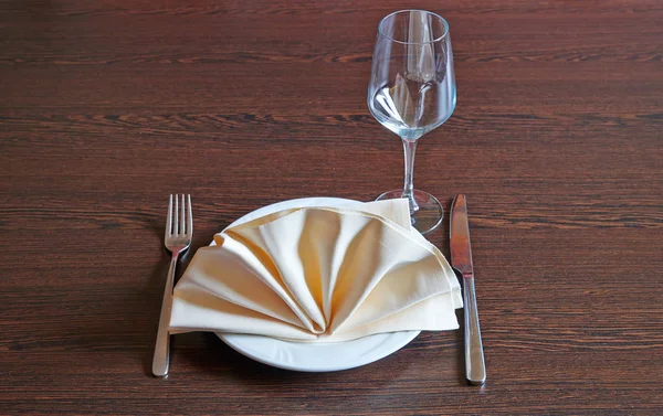Asciugamano su piastra bianca, forchetta e coltello su tavolo in legno — Foto Stock