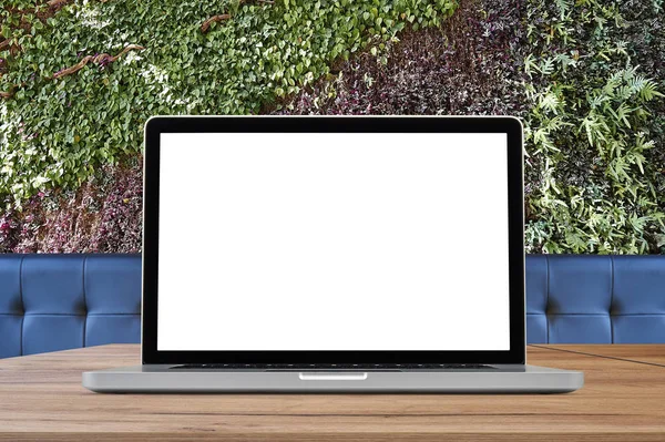Ноутбук на дерев'яному столі проти екологічної стіни листя — стокове фото