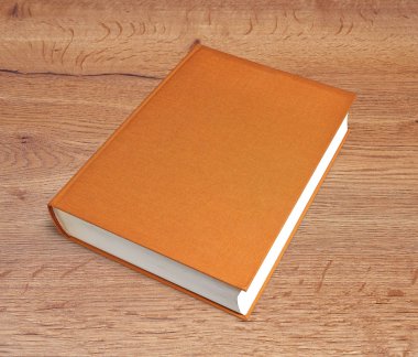 Kapalı kahverengi büyük bir kitap ve ahşap bir masa.