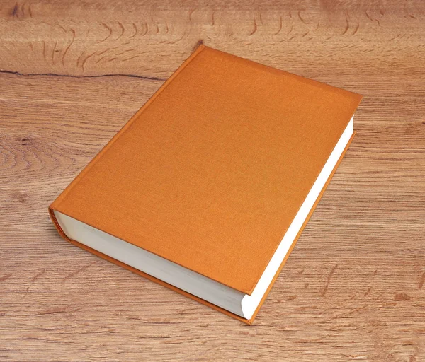 Closed brown big book with hardcover on wooden desk — Stock Photo, Image