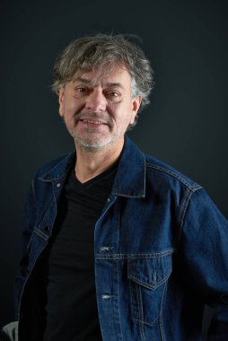 Arkaplanda mavi kot ceketli bir adamın portresi.