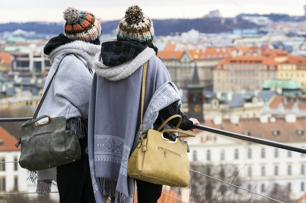 Two young women look at the Prague city from above, from the hill.