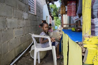 Las Terrenas, Dominik Cumhuriyeti - 26 Eylül 2016: bir bebek sandalyede oturuyor ve bazı meyve, kahve ve yapıştırıcı satış kimliği belirsiz küçük kız.