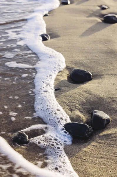 Берегова лінія з темним піском і маленькою галькою — стокове фото