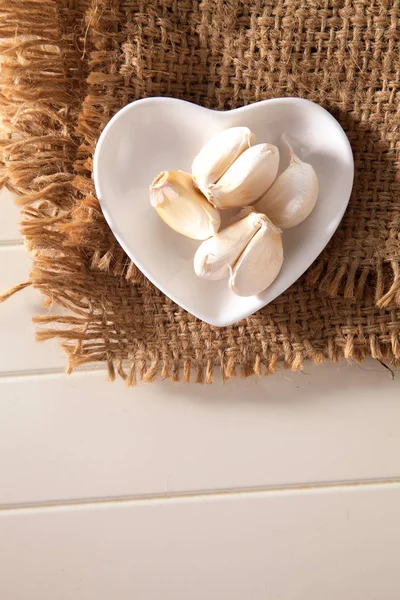 Garlic in heart shaped bowl — Stock Photo, Image