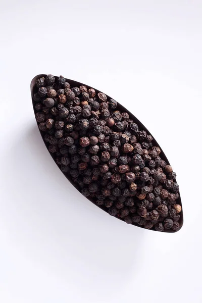Grani di pepe neri in piatto — Foto Stock