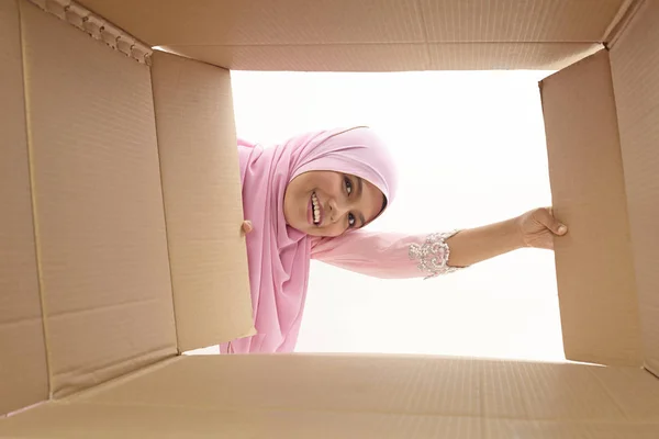 woman opening a carton box and looking inside, relocation and unpacking concept