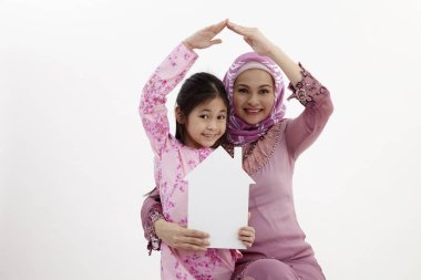 Küçük daughte yukarıda elleriyle evin çatı şekli oluşturan anne