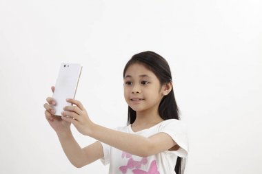 Çocukluk ve teknoloji. Akıllı telefon kullanan sevimli küçük kız. Beyaz izole.