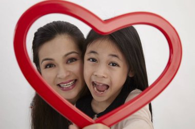 Malay anne ve kızı kamera karşı karşıya bir kırmızı kalp şekli resim çerçevesi holding