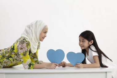 Anne ve kızı bir mavi boş kalp şekli karton tutan