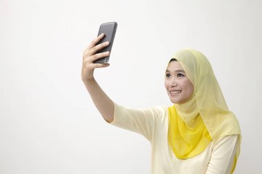 Malay kadın holding akıllı kullanarak telefon kendi kendine portre