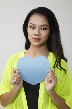 bir mavi renk kalp şekli kağıt tutan genç kadın