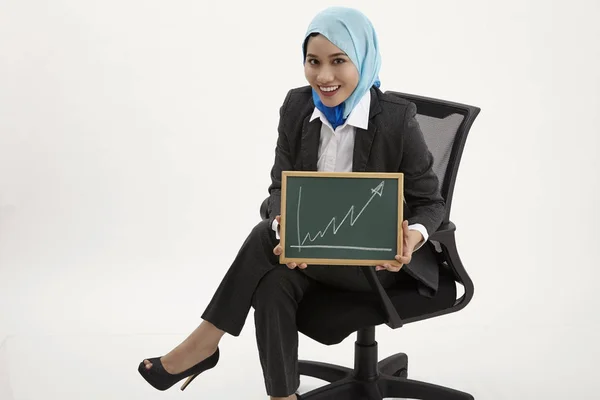Malaiische Geschäftsfrau Sitzt Auf Bürostuhl Und Hält Tafel Mit Diagrammaufstellung — Stockfoto