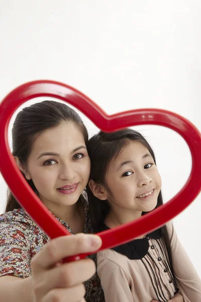 马来母亲和女儿抱着一个红色的心形相框面对摄像头 — 图库照片