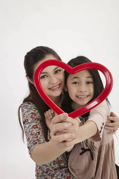 马来母亲和女儿抱着一个红色的心形相框面对摄像头 — 图库照片