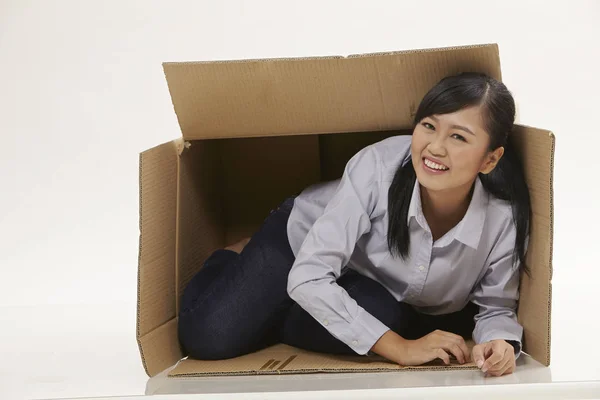 asian woman try to fit gerself to a small box