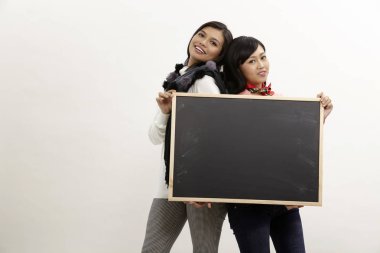 bir kara tahta tutan iki Asyalı kadınlar