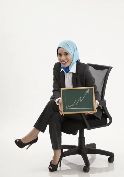 Malaiische Geschäftsfrau Sitzt Auf Bürostuhl Und Hält Tafel Mit Diagrammaufstellung — Stockfoto