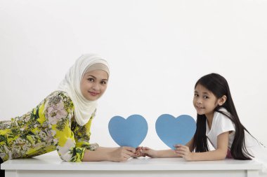 Anne ve kızı bir mavi boş kalp şekli karton tutan