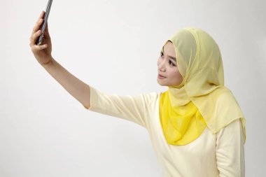 Malay kadın holding akıllı kullanarak telefon kendi kendine portre