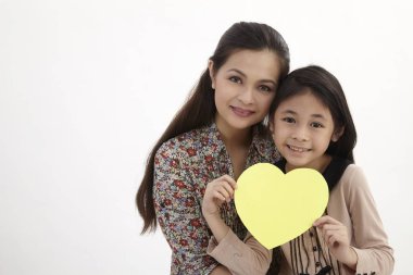 Anne ve kızı bir sarı boş kalp şekli kartını tutan