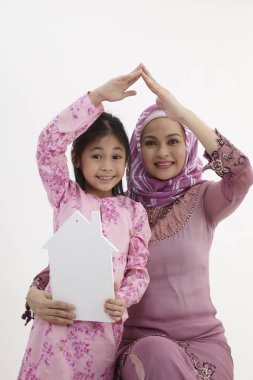 Küçük kızım yukarıda elleriyle evin çatı şekli oluşturan anne