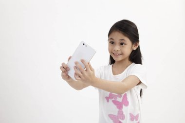 Çocukluk ve teknoloji. Akıllı telefon kullanan sevimli küçük kız. Beyaz izole.