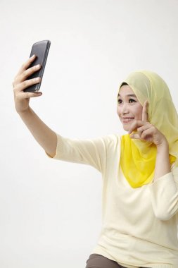 Malay kadın holding akıllı kullanarak telefon kendi kendine portre