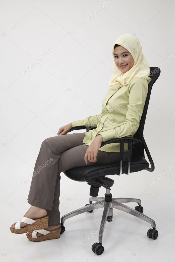Happy malay business woman sitting on a chair