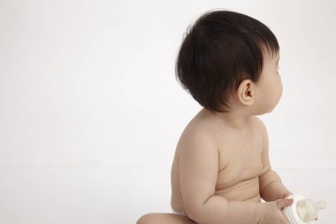 oturan Çinli bebek kız geri arıyorsunuz bir süt şişesi holding