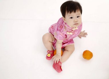 Çinli bebek tutan bir portakal cheomgsam giyiyor   