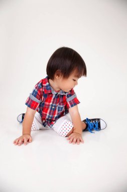 Çinli çocuk beyaz arka plan üzerinde oturan stüdyo çekim