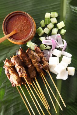 Malezya gıda satay üstten görünüm salatalık, soğan ve keupat ile muz yaprak üzerinde