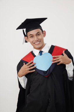 bir kalp şekli kartını tutan malay mezun öğrenci 