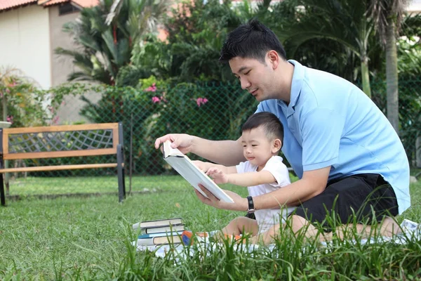 father and son reading at their garden