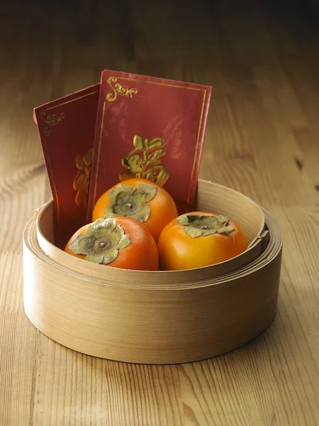 persimmons in a basket o with chinese red envelope
