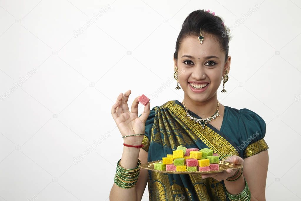cheerful indian lady holding tray of candy