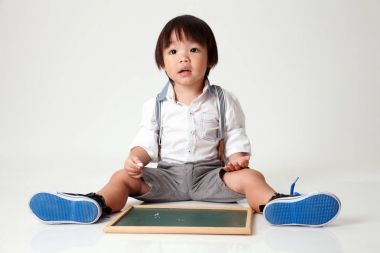 siyah baord önünde oturan çocuk