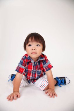 Çinli çocuk beyaz arka plan üzerinde oturan stüdyo çekim