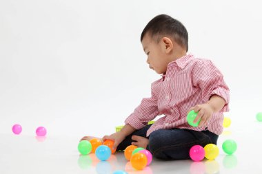 Çinli çocuk beyaz arka plan üzerinde renkli topları oynamak
