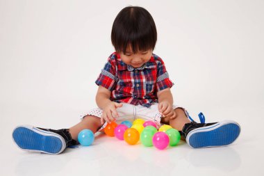 Çinli çocuk oynamak renkli topları önünde oturan