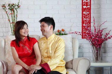 Çinli çift Çin yeni yılı dekorasyon tebrik ile kanepede oturan