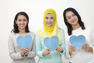 Üç multi ırksal Malezya holding kalp şekli karton kameraya bakıyor