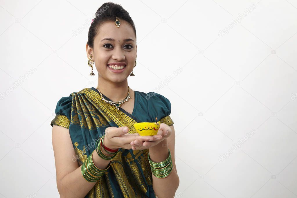 woman wearing saree holding a yellow oil lamp