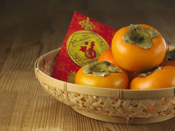 persimmons in a basket o with chinese red envelope-ang pao